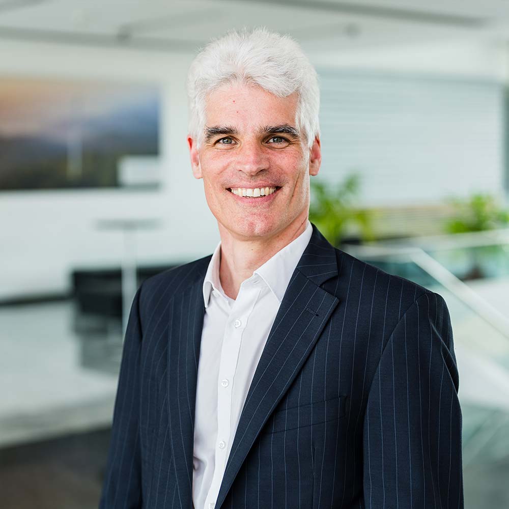 Michael Klein, Geschäftsführer badenovaERNEUERBARE: Mann im mittleren Alter mit weißen Haaren und im Anzug lacht in die Kamera