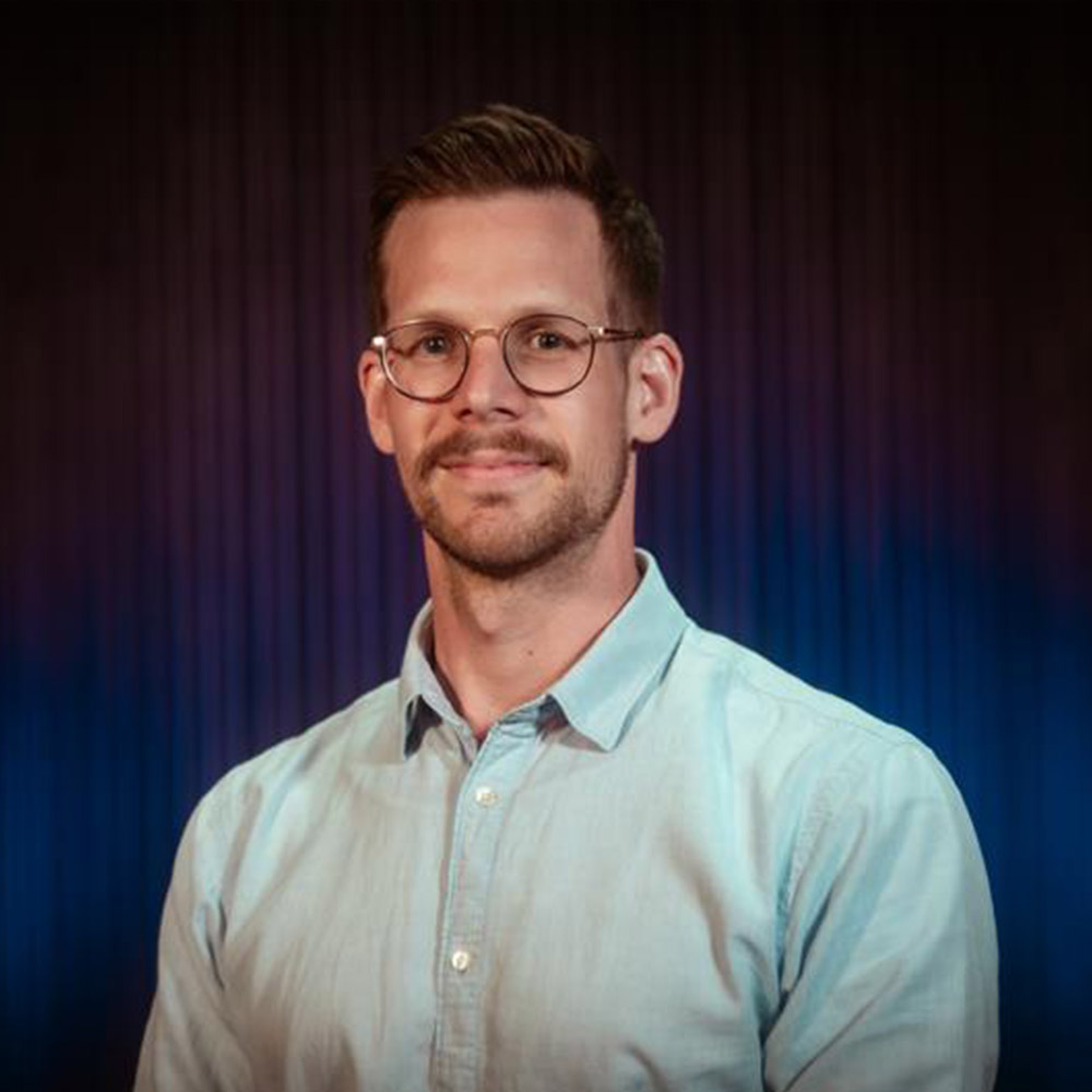 Nils Müller, VerNETZt: Junger Mann mit Brille, braunen Haaren und hellem Hemd sieht freundlich in die Kamera