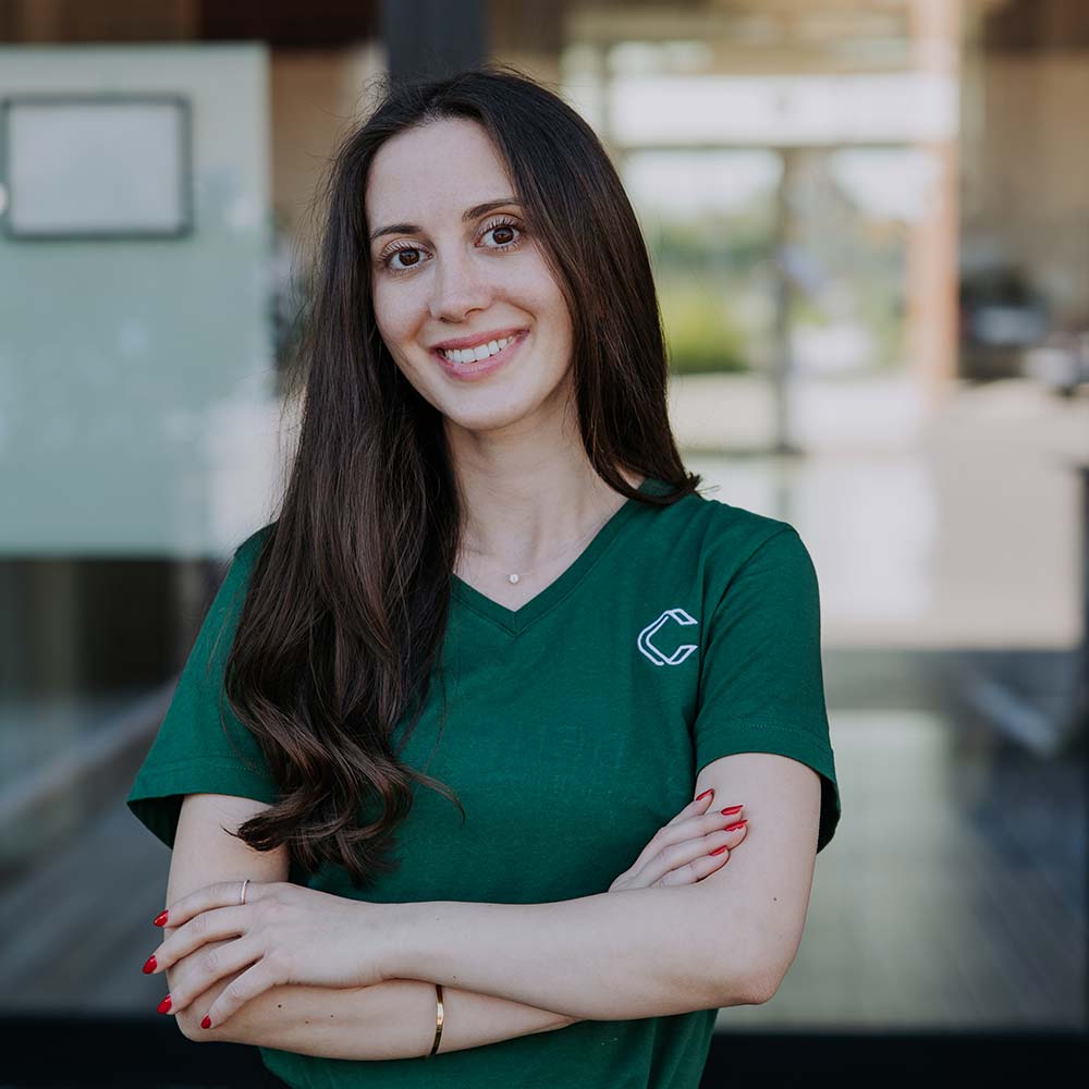 Vanya Andonova, Innovation Consultant: Junge Frau mit langen, dunkelbraunen Haaren in grünem T-Shirt mit verschränkten Armen lächelt in die Kamera